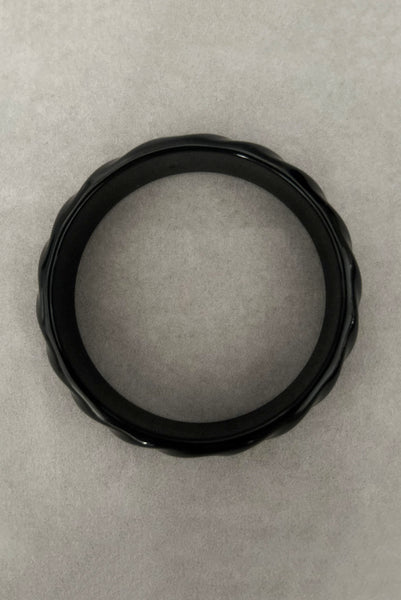 Vertical top view of 1980s vintage black plastic twisted, ridged, and orange goldfish painted bangle bracelet set of three (3). Showing the ridged bangle only.