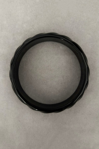 Vertical bottom view of 1980s vintage black plastic twisted, ridged, and orange goldfish painted bangle bracelet set of three (3). Showing the ridged bangle only.