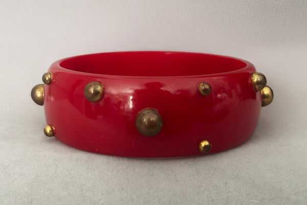 Horizontal back view of 1940s vintage brass studded rich cherry red Bakelite statement bangle bracelet.