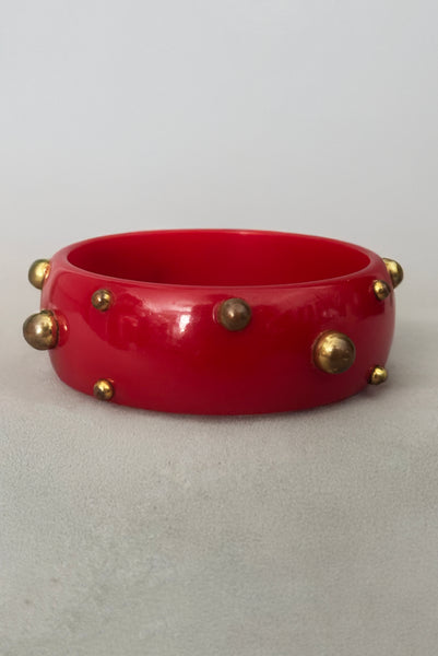 Vertical back view of 1940s vintage brass studded rich cherry red Bakelite statement bangle bracelet.