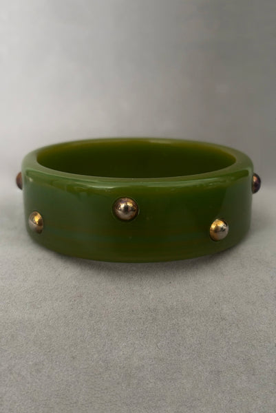 Vertical back view of 1960s vintage striated green plastic bangle bracelet with gold tone studs. Showing discoloration of the studs.