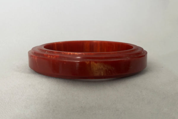 Horizontal front view of 1940s vintage groove carved rust and yellow marbled Bakelite bangle bracelet.