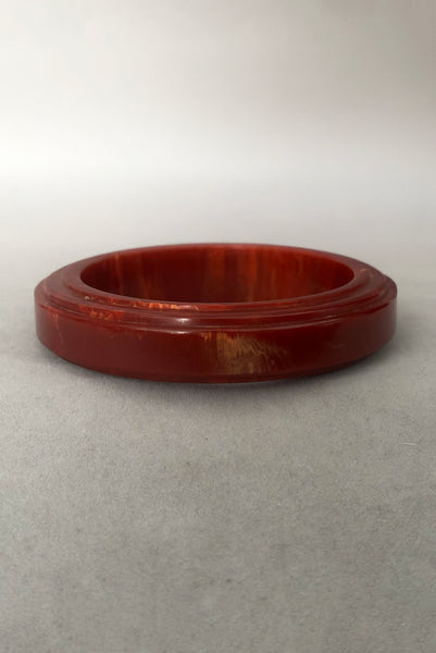 Vertical front view of 1940s vintage groove carved rust and yellow marbled Bakelite bangle bracelet.