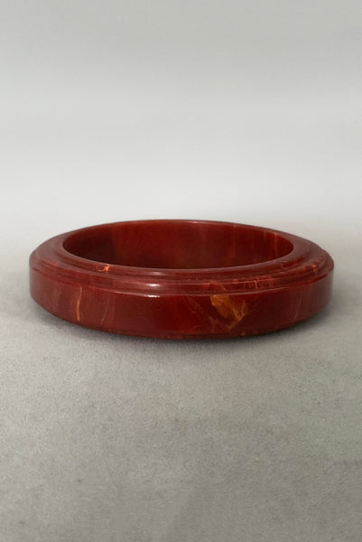 Vertical back view of 1940s vintage groove carved rust and yellow marbled Bakelite bangle bracelet.