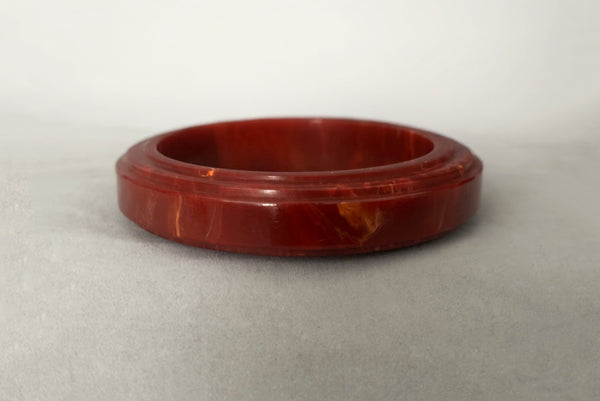 Horizontal back view of 1940s vintage groove carved rust and yellow marbled Bakelite bangle bracelet.