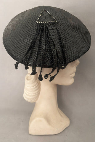 Vertical side view of 1960s vintage rhinestone trimmed black glossy straw beret with straw fringe, by Jack McConnell.