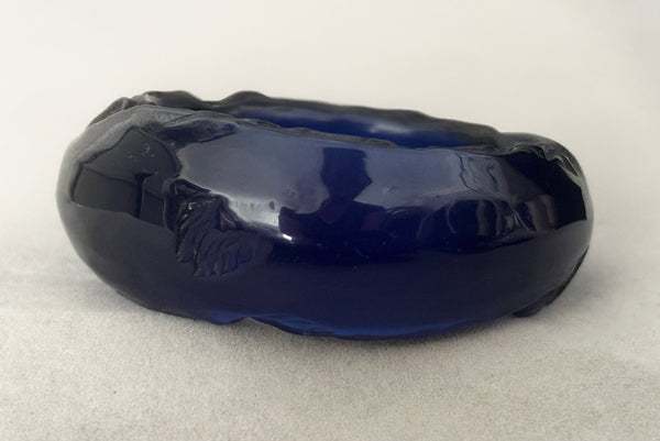 Horizontal front view of 1980s vintage artisan carved translucent blue Lucite asymmetrical bangle bracelet.