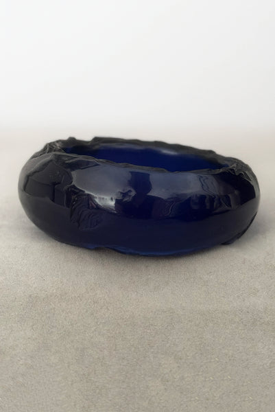 Vertical front view of 1980s vintage artisan carved translucent blue Lucite asymmetrical bangle bracelet.