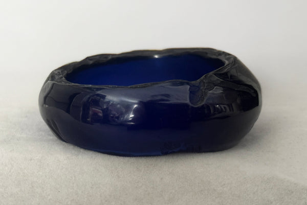 Horizontal back view of 1980s vintage artisan carved translucent blue Lucite asymmetrical bangle bracelet.