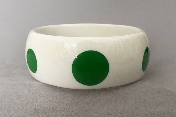 Horizontal front view of 1980s vintage green and white polka dot plastic domed bangle bracelet.