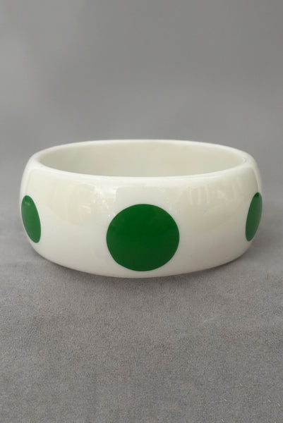 Vertical front view of 1980s vintage green and white polka dot plastic domed bangle bracelet.