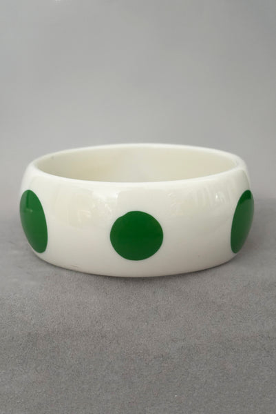Vertical side view of 1980s vintage green and white polka dot plastic domed bangle bracelet.