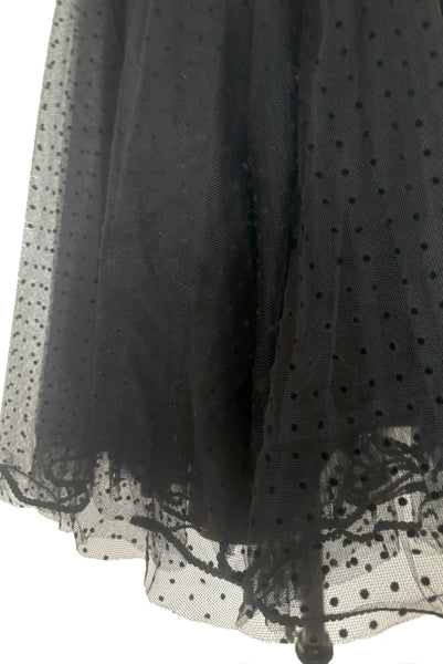 Hem detail view of 1980s vintage black satin, sequin lace, & dotted tulle asymmetrical cocktail dress by Mignon, small to medium. New with tags. Showing the black polka dot tulle skirt edged with black sequins.