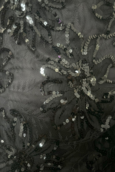 Detail view of 1980s vintage black satin, sequin lace, & dotted tulle asymmetrical cocktail dress by Mignon, small to medium. New with tags. Showing a close-up of the sequin floral lace and black satin fabric. 