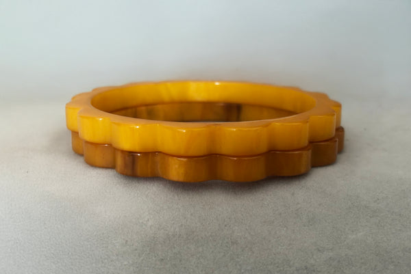 Horizontal front view of 1930s vintage pair of yellow marbled egg yolk and butterscotch scalloped or daisy Bakelite bangle bracelet set of two (2).