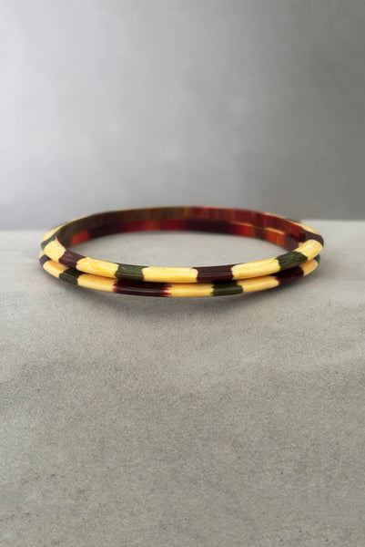 Vertical front view of 1960s vintage cream, purple, and green celluloid two (2) bangle bracelet set. Showing the pair of bangles together.