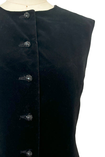 Bodice front detail view of 1960s vintage black velveteen rhinestone button front drop waist jumper dress, small to medium. Showing the black plastic buttons studded with black rhinestones.
