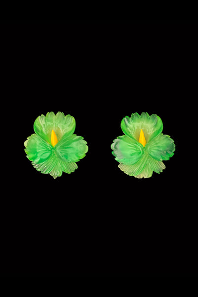 Vertical front view of 1960s vintage translucent green and yellow Lucite hibiscus tropical floral clip-on earrings.