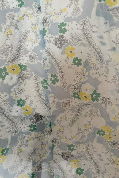 Fabric detail of 1940s sheer blue nylon green and yellow floral & spiderweb novelty print dress, small to medium. Showing the yellow, green, white, black, and blue print.