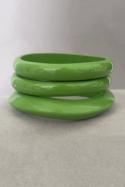 Vertical front view of 1980s vintage leaf green two (2) domed, and one (1) saucer three (3) bangle bracelet set. Showing the three bangles stacked.