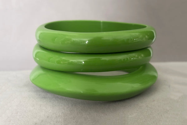 Horizontal front view of 1980s vintage leaf green two (2) domed, and one (1) saucer three (3) bangle bracelet set. Showing the three bangles stacked.