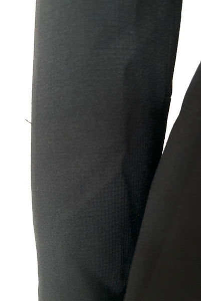 Detail view of 1970s vintage midi length black and orange wool coat with belt, by Gloria Sachs, size small to medium. Showing minor damage to the black wool.