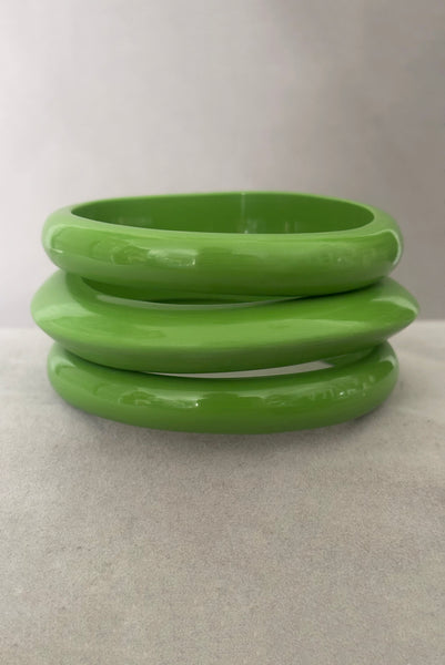 Vertical front view of 1980s vintage leaf green two (2) domed, and one (1) saucer three (3) bangle bracelet set. Showing the three bangles stacked.