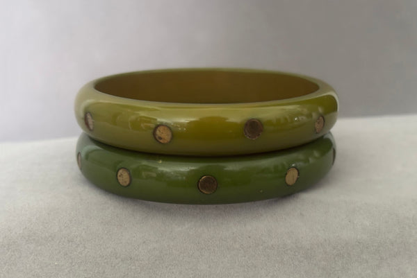 Horizontal front view of 1980s vintage green plastic two (2) bangle bracelet set inlaid with gold tone brass dots. Showing the two bangles together.