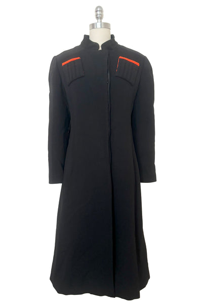 Front view of 1970s vintage midi length black and orange wool coat with belt, by Gloria Sachs, size small to medium.