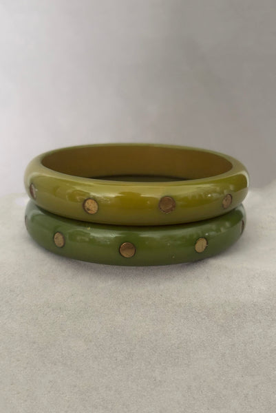 Vertical front view of 1980s vintage green plastic two (2) bangle bracelet set inlaid with gold tone brass dots. Showing the two bangles together.