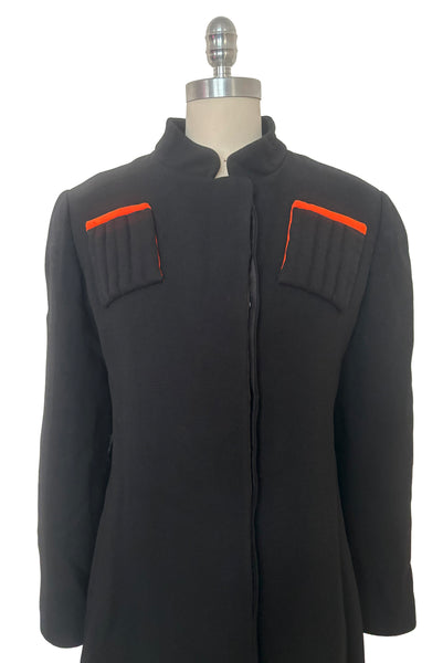 Bodice front view of 1970s vintage midi length black and orange wool coat with belt, by Gloria Sachs, size small to medium.