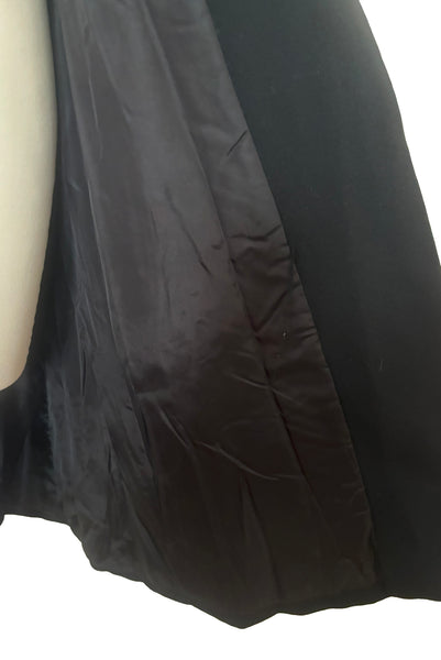 Interior detail view of 1970s vintage midi length black and orange wool coat with belt, by Gloria Sachs, size small to medium. Showing the black synthetic lining. 