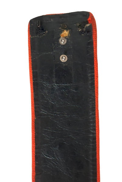 Belt detail view of 1970s vintage midi length black and orange wool coat with belt, by Gloria Sachs, size small to medium. Showing some damage to the backing on the belt. Including a missing snap. 