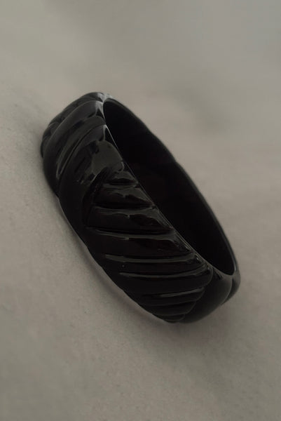 Vertical perspective view of 1980s vintage black plastic molded bangle bracelet.