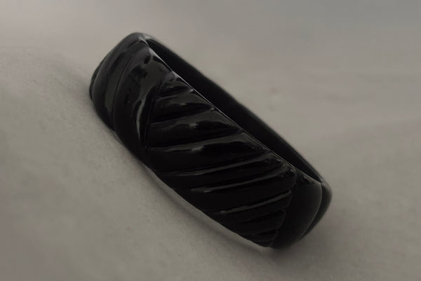 Horizontal perspective view of 1980s vintage black plastic molded bangle bracelet.