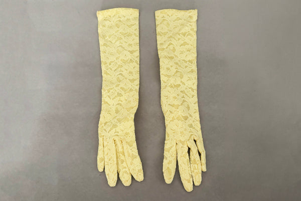 Horizontal front view of 1960s vintage below elbow yellow stretch lace gloves.