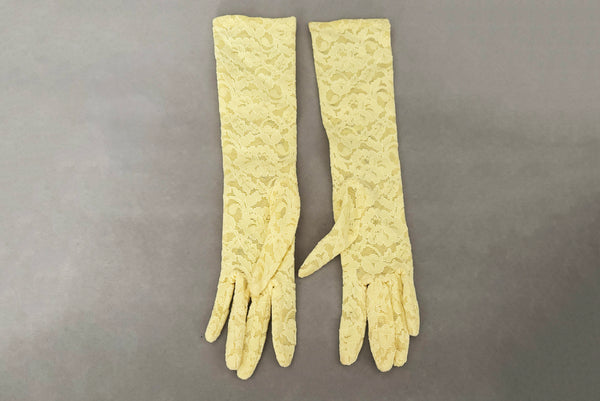 Horizontal back view of 1960s vintage below elbow yellow stretch lace gloves.