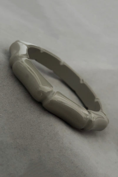Vertical perspective view of 2000s y2k vintage gray plastic molded faux bamboo bangle bracelet.