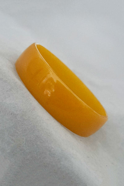 Vertical perspective view of 1940s vintage egg yolk yellow and mustard marbled Bakelite domed bangle bracelet