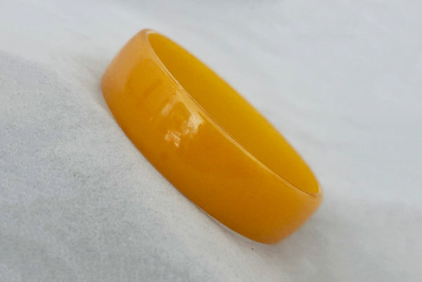 Horizontal perspective view of 1940s vintage egg yolk yellow and mustard marbled Bakelite domed bangle bracelet