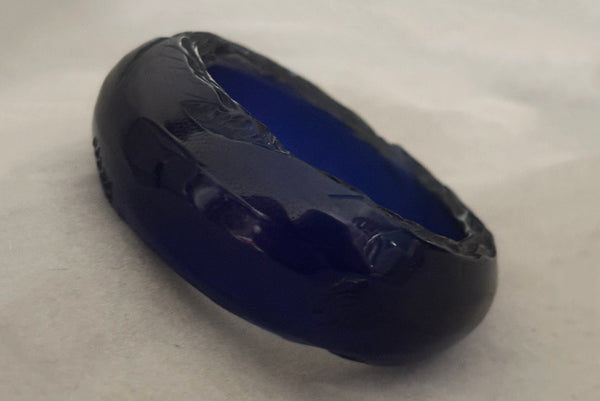Horizontal perspective view of 1980s vintage artisan carved translucent blue Lucite asymmetrical bangle bracelet.