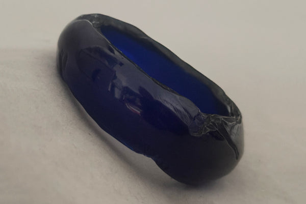 Horizontal perspective view of 1980s vintage artisan carved translucent blue Lucite asymmetrical bangle bracelet.