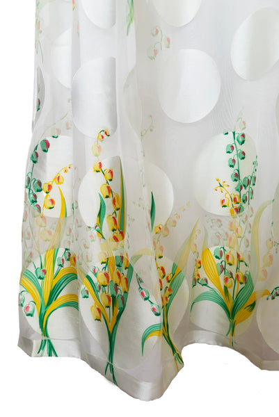 Detail view of 1960s vintage white chiffon, satin polka dot, yellow and green lily of the valley print floral maxi dress by Richilene New York for Neiman Marcus, size small to medium. Showing the lily of the valley floral border printed hem.