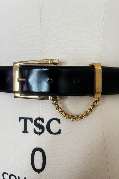 Detail view of 1990s vintage black leather and gold chain buckle designer belt by Ellen Tracy, size extra small to small. Showing the gold tone buckle and retainer attached with a chain. Please note the touch wear to the metal.