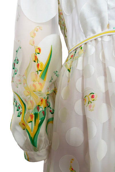 Detail view of 1960s vintage white chiffon, satin polka dot, yellow and green lily of the valley print floral maxi dress by Richilene New York for Neiman Marcus, size small to medium. Showing the long full sleeves with fitted cuff and the vibrant yellow, green, and red floral print.