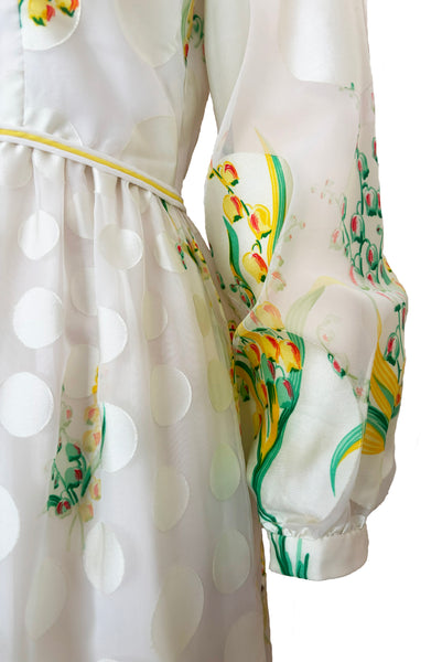 Detail view of 1960s vintage white chiffon, satin polka dot, yellow and green lily of the valley print floral maxi dress by Richilene New York for Neiman Marcus, size small to medium. Showing the long full sleeves with fitted cuff and the vibrant yellow, green, and red floral print.