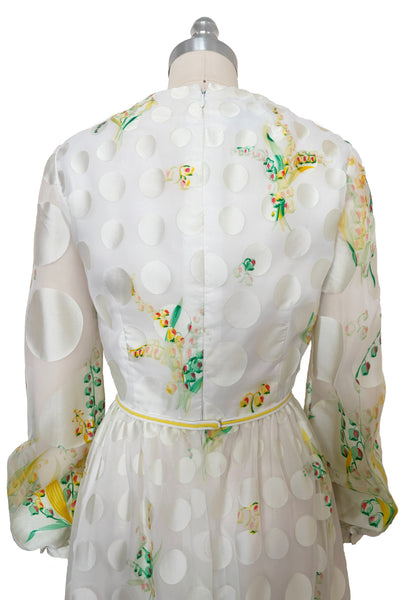Bodice back view of 1960s vintage white chiffon, satin polka dot, yellow and green lily of the valley print floral maxi dress by Richilene New York for Neiman Marcus, size small to medium. Showing the high rear neckline, long full sleeves, and elevated waist with white and yellow cord bow belt.