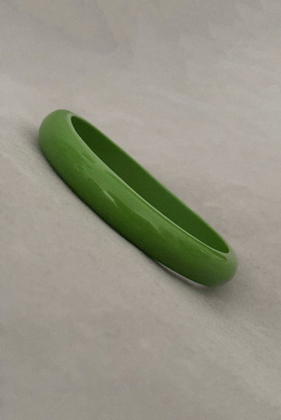 Vertical perspective view of 1980s vintage leaf green two (2) domed, and one (1) saucer three (3) bangle bracelet set. Showing one domed bangle.