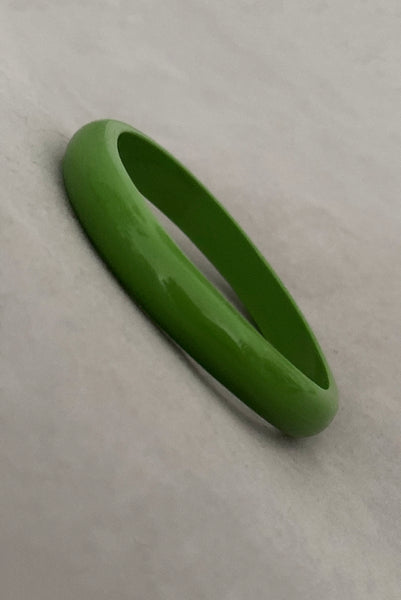 Vertical perspective view of 1980s vintage leaf green two (2) domed, and one (1) saucer three (3) bangle bracelet set. Showing one domed bangle.