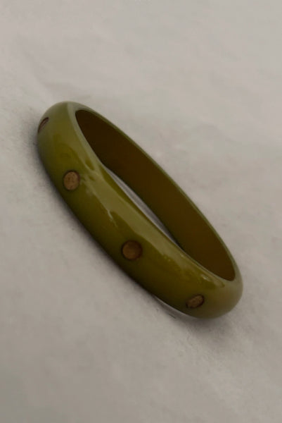 Vertical perspective view of 1980s vintage green plastic two (2) bangle bracelet set inlaid with gold tone brass dots. Showing the lighter bangle.
